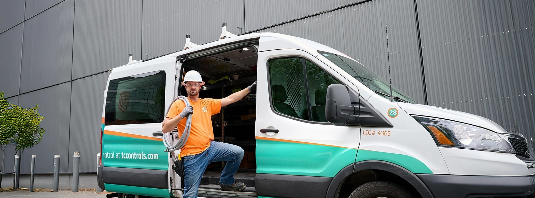 TC Controls technician standing beside a branded service van outside an industrial building